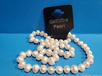 Photo showing white cultured pearl necklace with a tag labeled 'Genuine Pearl'