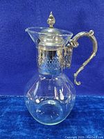 Full view of the glass claret carafe showing bulbous body and silver plated lid and handle.