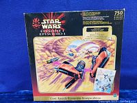 Front and top view of the unopened Star Wars Episode I 750 piece jigsaw puzzle box showing podracing artwork and branding details.