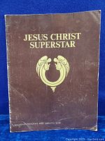 Front cover of the souvenir program showing gold embossed title and symbol on brown background with signs of creasing.