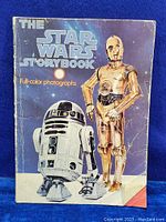 Full front cover of the vintage 1978 Star Wars Storybook showing R2-D2 and C-3PO on a blue background, with visible surface wear and edge creases.