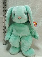 Front view of the green plush rabbit with measuring scale showing height approximately 13.5 inches.