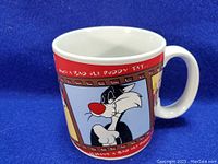 Side view of white ceramic coffee mug with printed graphics featuring Sylvester Cat from Looney Tunes, showing colorful artwork and handle.