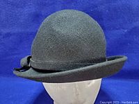 Front angle of the vintage black wool hat showing rounded crown and rolled brim with bow.