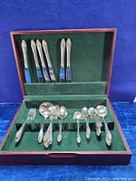 Vintage Community Plate silverware set displayed in green felt-lined wooden canteen chest showing forks, spoons, and knives with ornate patterned handles.