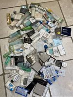 Photo showing a large assortment of hotel-sized toiletries including small bottles, tubes, bars, and packets in various colors and packaging styles.