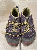 Top front view of dark gray and pink women’s hiking sneakers with yellow laces on tiled floor.