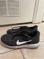 Side view of black Nike sneakers with white swoosh and white sole.
