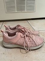 Side view of women's pink rose Sketchers sneakers, size 7.5, showing woven upper and white sole with slight dirt marks.