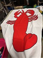 Red lobster embroidered on white fabric flag, showing large detailed claws and body.