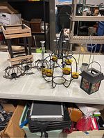 Seven assorted candle holders including metal and wooden lantern styles, round metal holders with amber glass cups, stained glass floral lantern, and rustic wooden frame lantern.