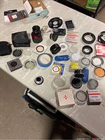 Overview of camera accessories, lenses, and numerous filters laid out on a table showing condition and variety