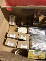 Top view of assorted labeled boxes of screws and nails including Grip-Rite and Allied Bolt & Screw brands, showing various sizes and types.