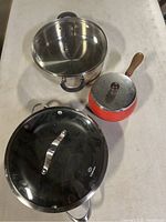 Top view of all four pans on a table showing their lids and handles