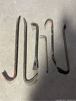 Photo showing six crowbars of varying lengths and designs laid side by side on a concrete floor.