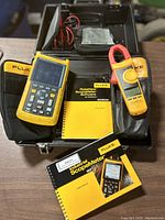 Open case showing two handheld meters, user manuals, leads and accessories