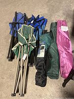 Photo showing the six folded chairs in assorted colors (blue, green, black, pink) with their carrying bags tied around the frames