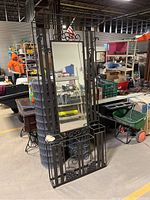 Full view of the tall ornate metal hallway tree with mirror reflecting the warehouse environment.