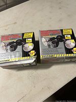 Two boxed LiteAide motion sensing security lights on a white surface.