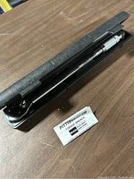 Torque wrench inside black plastic branded Pittsburgh carrying case with instruction manual visible.