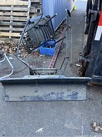 Full view of plow attachment showing curved metal blade with control handles and mounting frame
