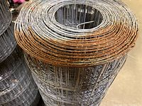 Close-up of the welded wire fencing showing rust along the upper edge and the dense grid pattern of the wire mesh.