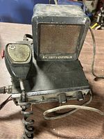 Front view of vintage Motorola dispatch radio showing the base unit with two control knobs, attached microphone on left side, and external speaker mounted on top.