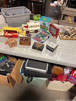 Table display with various vintage toys including Fisher Price vehicles, Etch A Sketch, chessboard, small boxed games, and miscellaneous small toys.