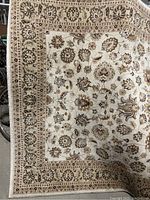 Top view showing the full Welbourne area rug with cream background and detailed floral patterns with red and blue accents.