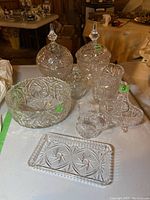 Full view of all eight crystal and glassware pieces arranged on a table with visible prices on some items.