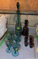 Two glass decanter sets with their matching glasses arranged on a countertop.