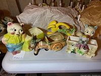 Lot of five farm animal ceramic figurine holders displayed on table with brown paper and white cloth in background. Includes pig, donkey, duck, two mice figurines in pastel colors.