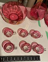 Red punch bowl, six glasses with metal handles, and large red glass snifter shown with scale for size reference.