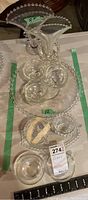 Two clear glass vases with ball edge trim and beaded handles, displayed next to a glass platter and punch glasses.