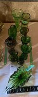Group of assorted green glass vases on display surface