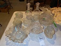 Photo of entire glassware set including two matching decanters, bowls, plates, and tray on table surface.