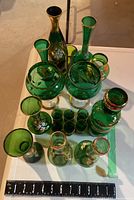 Top view of 18 green glass pieces showing shape variety and gold painted details