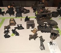 Collection of metal miniature castings including a cast iron stove, cash register, scale, animal figures, and other small household items.