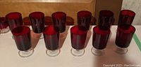 Set of ruby glass goblets roughly 5 inches tall, arranged in two rows on white surface.