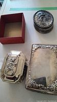 Top view of three silverplated boxes showing design details and open velvet-lined interiors.