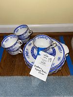 Photograph of four bone china cups stacked with plates underneath, showing Blue Rhapsody pattern.