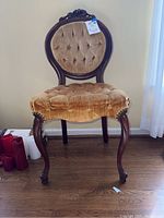Front view of vintage accent chair showing gold velvet button tufted seat and backrest, dark wood frame and curved legs