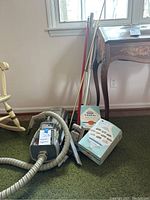 Full view of Electrolux vacuum cleaner and accessories set against green carpet and beige wall.