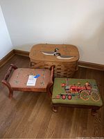 Two needlepoint covered wooden footstools placed on hardwood floor with large woven basket behind.