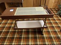 Side view of vintage warming cart with glass warming tray and wood frame, showing overall structure and wheels.