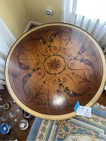 Top view showing the round wooden table top with floral inlay design and starburst center pattern.