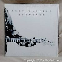 Front cover of Eric Clapton Slowhand vinyl album featuring black and white guitar image and artist name/title.