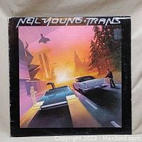 Front cover of Neil Young Trans album showing stylized futuristic city with cars and sunset.