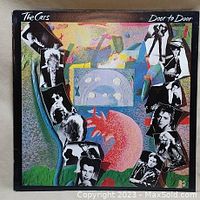 Front cover of The Cars 'Door to Door' album featuring artistic collage with band member images.