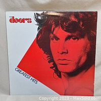 Front of The Doors Greatest Hits album cover showing red and white design with portrait of Jim Morrison